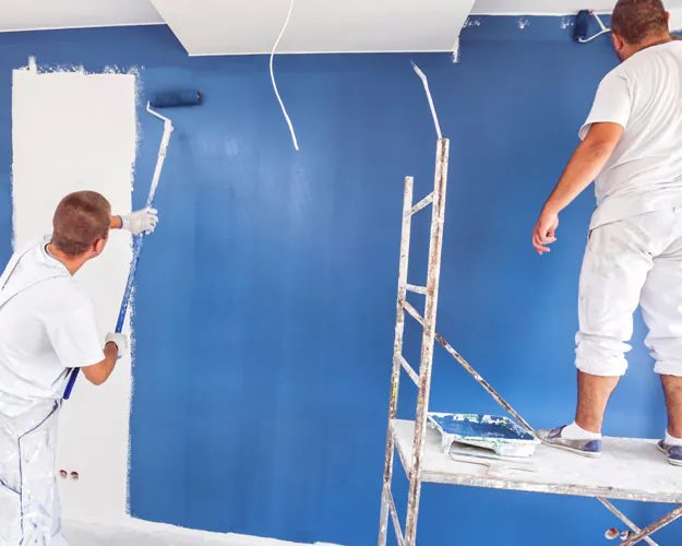 Schilders brengen verf aan op een binnenmuur